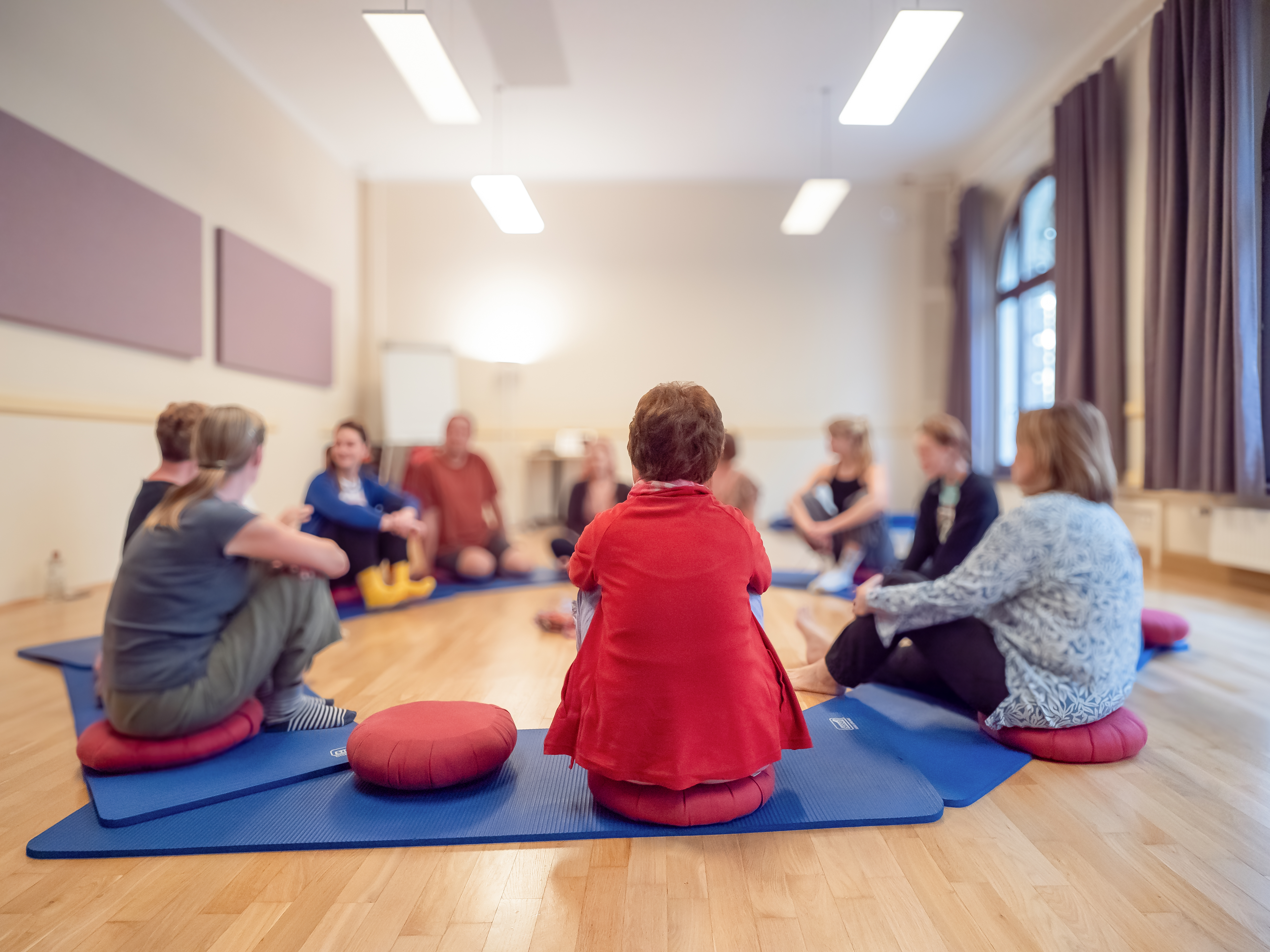 Erfahrungsbericht Biodanza Sitzkreis Teilnehmer des Biodanza-Kurses sitzen am Boden in einem Kreis und unterhalten sich, Begegnung und Kennenlernen, andere Teilnehmende, die Methode