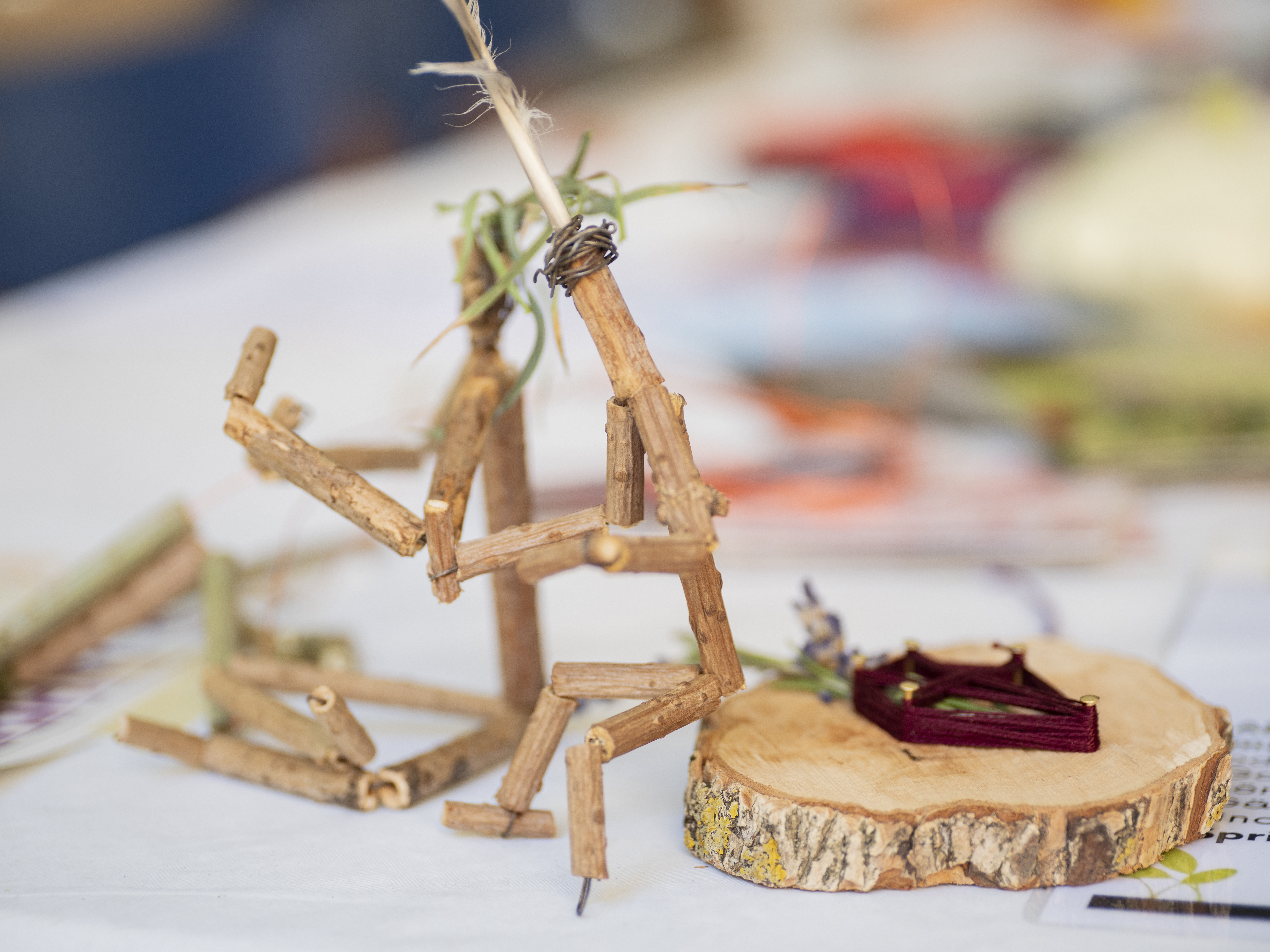 Holundermännchen Sommerfest 2024 zwei filigrane Figuren aus Holunderzweigen sitzen auf einer Baumscheibe